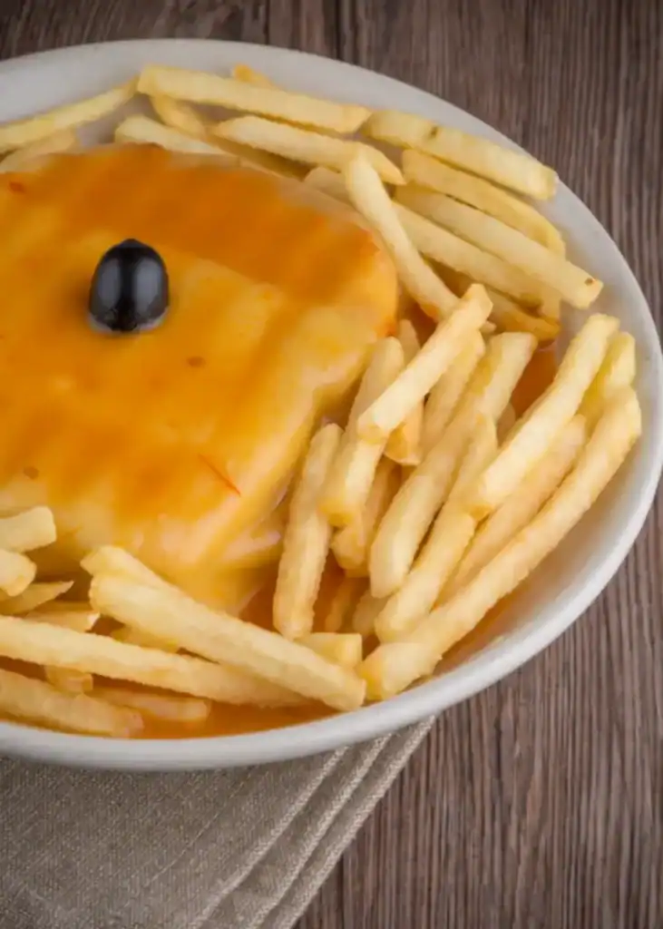 La francesinha de Porto, nappée de sauce à la bière et servie avec des frites croustillantes.