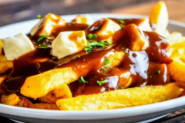 sauce brune au Thermomix versée sur des frites avec du fromage en grains dans une assiette