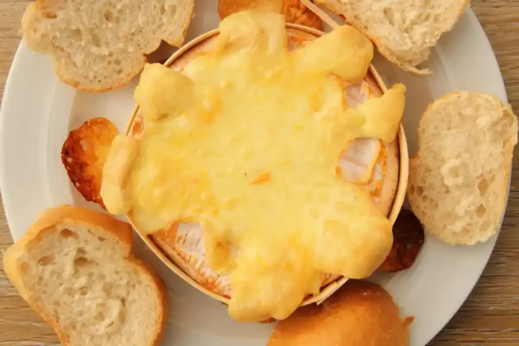 camembert rôti au four coulant dans sa boîte en bois servis avec du pain grillé