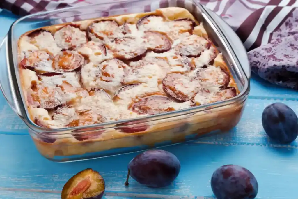 Clafoutis aux prunes maison, moelleux et doré, saupoudré de sucre glace.