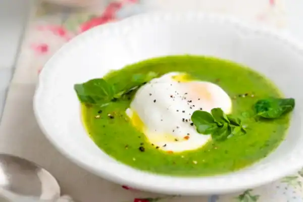 Velouté de cresson au Thermomix vert vif servi avec un filet de crème